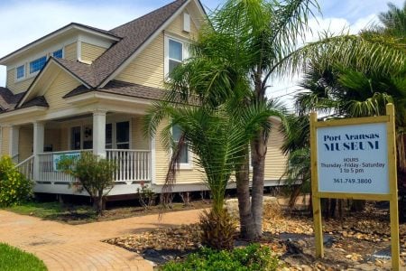 Port A Museum sign with historic house and palm trees in the background.