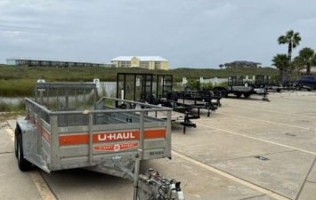 RV trailers and U-Haul trailer in parking lot at Gulf Waters Beach Front RV Resort.