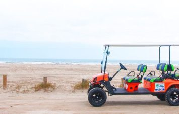 Golf cart parked on sandy beach near the Gulf of Mexico, showcasing golf cart-friendly access at Gulf Waters Beach Front RV Resort.