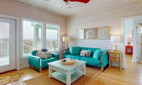 Bright living room with beach view, turquoise sofas, and coastal decor at Gulf Waters.