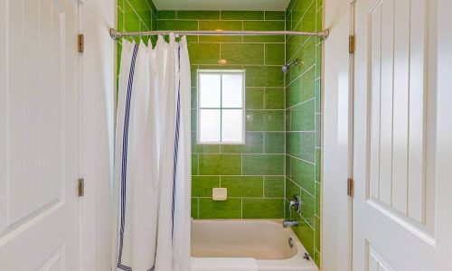 Bathroom with green tiled walls, bathtub, and window at Gulf Waters Beach Front RV Resort.