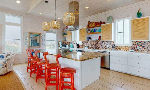 Bright, modern kitchen at Gulf Waters Beach Front RV Resort with island and red chairs.
