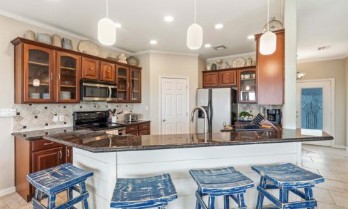 Modern kitchen at Gulf Waters Beach Front RV Resort with island and blue stools.
