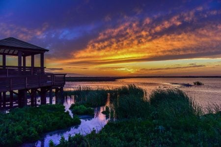 Scenic sunset over Gulf Waters Beach Front RV Resort with water and greenery.