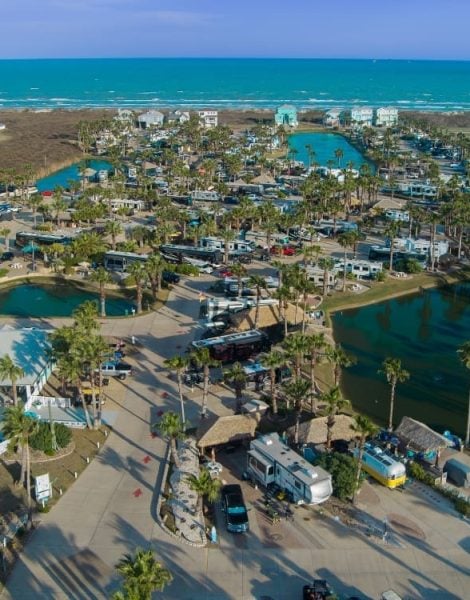 Aerial view of Gulf Waters Beach Front RV Resort showcasing RV sites, palm trees, and nearby water features, emphasizing the resort's layout and vacation atmosphere.