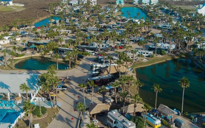 Aerial view of Gulf Waters Beach Front RV Resort with pools, RVs, and ocean in the background.