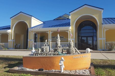 Port Aransas Community Theatre building with colorful exterior, featuring decorative sandcastle sculpture in foreground, located in Port Aransas, Texas.
