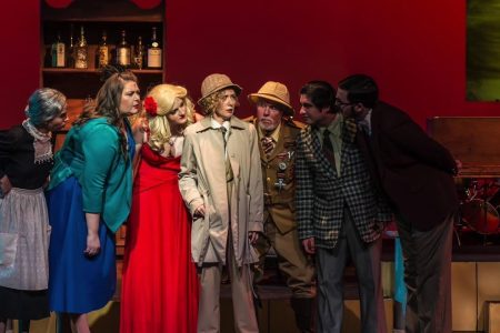 Cast of Harbor Playhouse Community Theatre performing a dramatic scene with characters in costumes, set against a vibrant stage backdrop.
