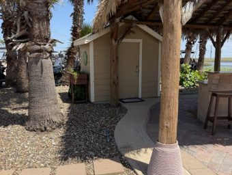 Beachfront RV resort with palm trees, shaded area, and small shed.